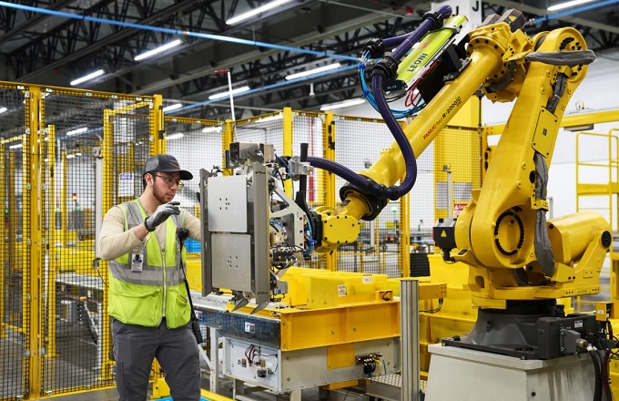 Empleado de un centro logístico de Amazon manipulando un robot