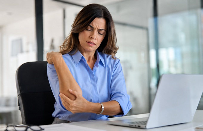 Mujer en una oficina con dolor de codo